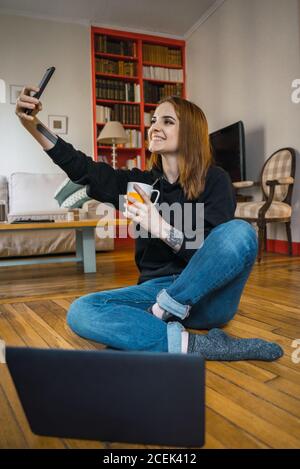 Femme prenant le selfie assis sur le sol Banque D'Images