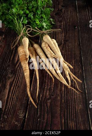 Bouquet de racines de persil avec des feuilles vertes sur bois foncé carte Banque D'Images