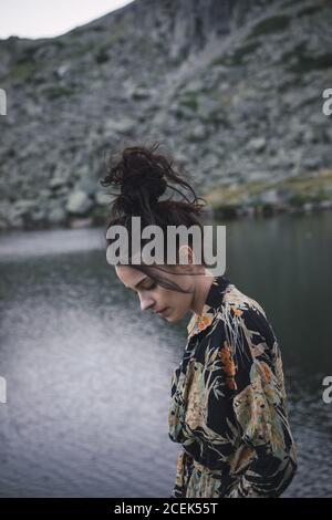 Jeune femme debout près d'un lac rippant Banque D'Images