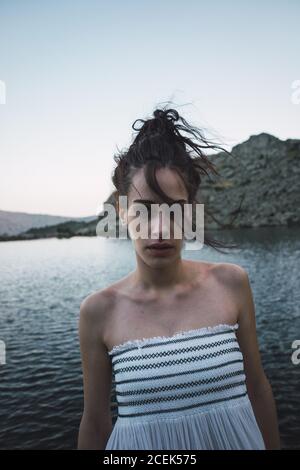 Jeune femme debout près d'un lac rippant Banque D'Images