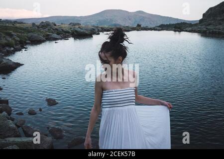 Jeune femme debout près d'un lac rippant Banque D'Images
