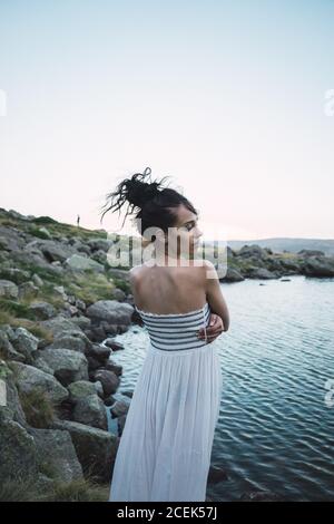 Jeune femme debout près d'un lac rippant Banque D'Images