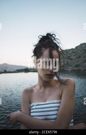 Jeune femme debout près d'un lac rippant Banque D'Images
