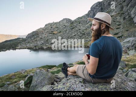 Jeune homme assis sur des rochers près du lac Banque D'Images