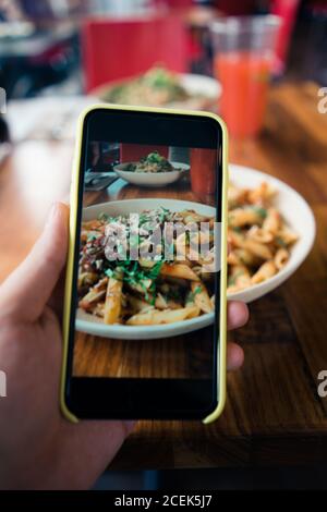 Rognez à la main en prenant une photo de bolognaise macaroni avec de la sauce à la viande avec tomate et fromage Banque D'Images