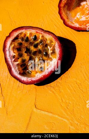 Photo d'un fruit de la passion coupé en deux sur fond jaune vif. Banque D'Images