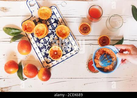 Main de femme préparant du jus d'orange de sang sur une table en bois blanc Banque D'Images