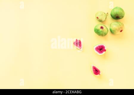 Figues vertes entières et coupées sur fond jaune, sur fond plat, dans l'espace de copie Banque D'Images