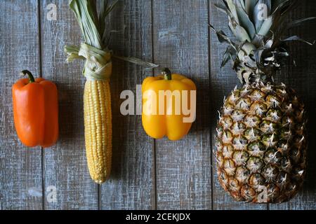 PARTY MIX: Un mélange de fruits et de légumes qui comprennent des poivrons, de l'ananas, et du maïs sur l'épi sont disposés ensemble sur une planche à découper en bois. Banque D'Images