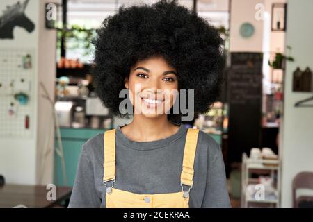 Bonne dame africaine avec des cheveux afro regarde les stands de caméra dans le café, tête de prise de vue. Banque D'Images