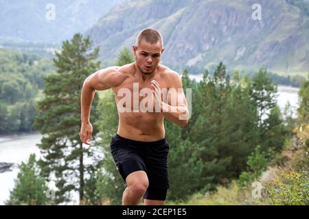 L'athlète sportif s'élève en amont dans la montagne, la rivière, les montagnes et la forêt. Course de sprint. Effet de mouvement et de course rapide, flou Banque D'Images