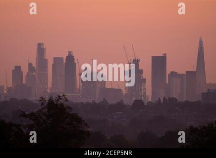 Wimbledon, Londres, Royaume-Uni. 1er septembre 2020. L'aube automnale au-dessus de Londres avec les gratte-ciels du bureau de la ville détourés contre un ciel changeant à l'approche du lever du soleil. Les maisons de banlieue et les arbres abondants au premier plan sont cueillis à travers les brumes d'automne basses. Crédit : Malcolm Park/Alay Live News. Banque D'Images