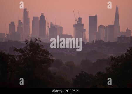 Wimbledon, Londres, Royaume-Uni. 1er septembre 2020. L'aube automnale au-dessus de Londres avec les gratte-ciels du bureau de la ville détourés contre un ciel changeant à l'approche du lever du soleil. Les maisons de banlieue et les arbres abondants au premier plan sont cueillis à travers les brumes d'automne basses. Crédit : Malcolm Park/Alay Live News. Banque D'Images