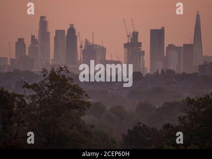 Wimbledon, Londres, Royaume-Uni. 1er septembre 2020. L'aube automnale au-dessus de Londres avec les gratte-ciels du bureau de la ville détourés contre un ciel changeant à l'approche du lever du soleil. Les maisons de banlieue et les arbres abondants au premier plan sont cueillis à travers les brumes d'automne basses. Crédit : Malcolm Park/Alay Live News. Banque D'Images