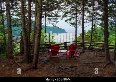 Chaises rouges à un point de vue pittoresque surplombant l'estuaire de la rivière point Wolfe à marée basse. Sentier Shiphaven, parc national Fundy, Nouveau-Brunswick, Canada. Banque D'Images