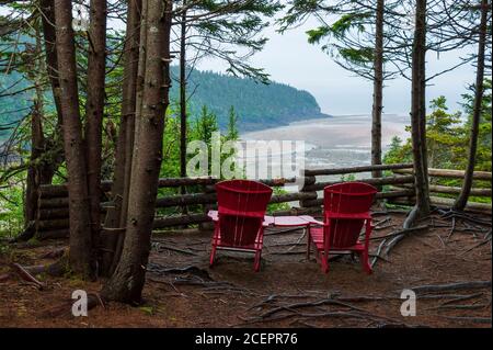 Chaises rouges à un point de vue pittoresque surplombant l'estuaire de la rivière point Wolfe à marée basse. Sentier Shiphaven, parc national Fundy, Nouveau-Brunswick, Canada. Banque D'Images