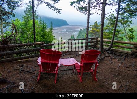 Chaises rouges à un point de vue pittoresque surplombant l'estuaire de la rivière point Wolfe à marée basse. Sentier Shiphaven, parc national Fundy, Nouveau-Brunswick, Canada. Banque D'Images