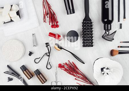 Accessoires de maquillage et produits cosmétiques noirs élégants avec vernis à ongles et plantes rouges sur fond de bois blanc, vue du dessus, espace de copie. Banque D'Images