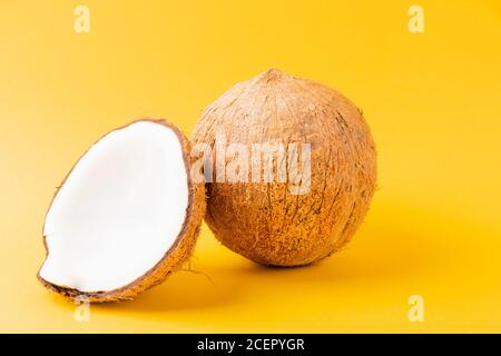 Happy Coconuts concept de jour, noix de coco fraîche et demi-noix de coco, prise studio isolée sur fond jaune Banque D'Images