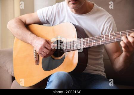 Détail du corps de la guitare acoustique et de l'homme jouant avec du blanc chemise à manches courtes et jean bleu Banque D'Images