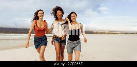 Des amis heureux qui s'amusent à courir sur la plage. Des femmes gaies entre amis pendant des vacances à la plage. Banque D'Images