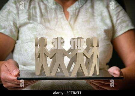 Figures en bois de personnes dans un cercle tenant les mains et debout sur la tablette. Le concept d'un réseau social, d'une entreprise ou d'autres relations. Réglage Banque D'Images