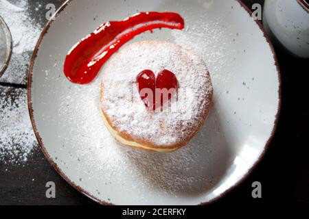 Donut rempli de gelée avec du sucre en poudre sur une plaque en céramique. Vue de dessus Banque D'Images