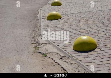 Trois hémisphères en béton jaune au bord du trottoir. Barrières architecturales empêchant les véhicules d'entrer dans la zone piétonne. Ville lif Banque D'Images