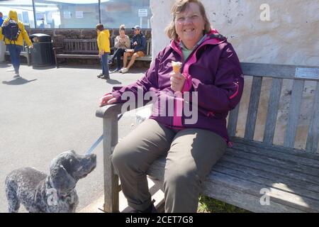 Femme avec glace et chien la regardant. Banque D'Images