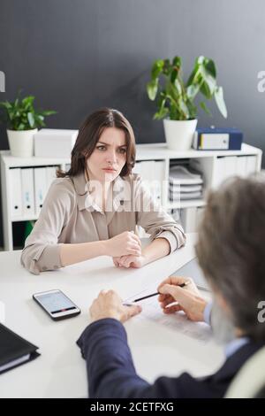 Une jeune femme se sent confondue avec des questions absurdes que le responsable des ressources humaines lui pose lors d'un entretien d'embauche, un cliché vertical grand angle Banque D'Images