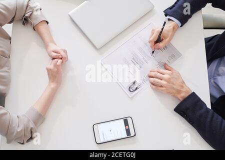 Directement frome au-dessus de la photo d'une femme méconnaissable assise devant De l'homme avec CV papier ayant entretien d'emploi Banque D'Images