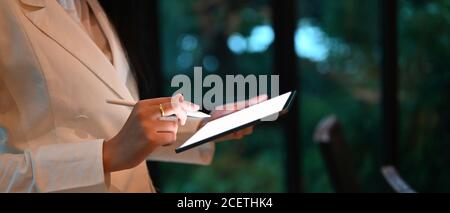 Prise de vue rognée femme d'affaires tenant une tablette de maquette et un stylet avec écran vide pour le montage. Banque D'Images