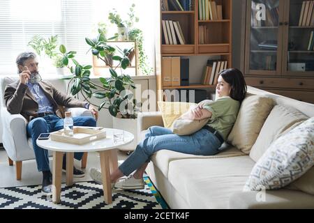 Jeune femme mélancolique assise sur un canapé embrassant oreiller la partageant pensées au psychologue pendant la séance de thérapie Banque D'Images