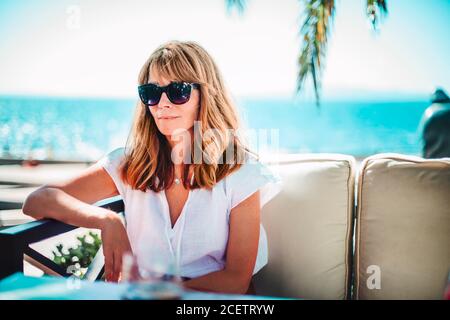 Portrait d'une femme heureuse bénéficiant du soleil d'été tout en se relaxant sur un canapé-salon en bord de mer. Banque D'Images