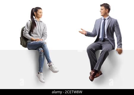 Une étudiante est assise sur un panneau vierge et parle à un homme en costume isolé sur fond blanc Banque D'Images