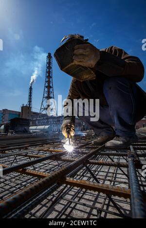 Plante d'engrais de Taraz. Construction d'une fondation ou d'un sous-sol en béton de renfort. Soudeur sur ciel bleu et smoki Banque D'Images