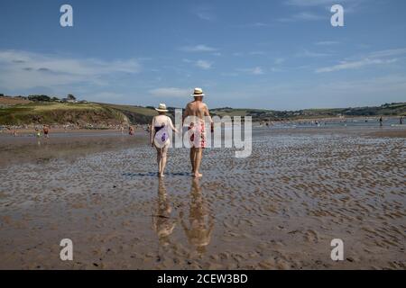 Un couple marchant le long de la plage de Bigbury-on-Sea surplombant l'île de Burgh, région d'une beauté naturelle exceptionnelle, côte sud-ouest du Devon, Angleterre, Royaume-Uni Banque D'Images