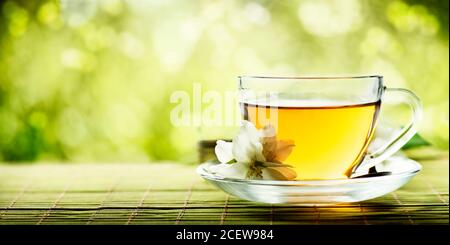 Tisane tasse de thé sur table en bois sur fond de bokeh vert nature avec espace. Boisson chinoise chaude dans la bannière de conception de tasse. Terres de plantation de thé Banque D'Images