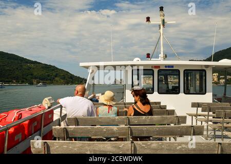 Une famille de derrière assise sur un ferry pour Porto Venere avec l'île de Palmaria en arrière-plan, le golfe de Poètes, la Spezia, Ligurie, Italie Banque D'Images