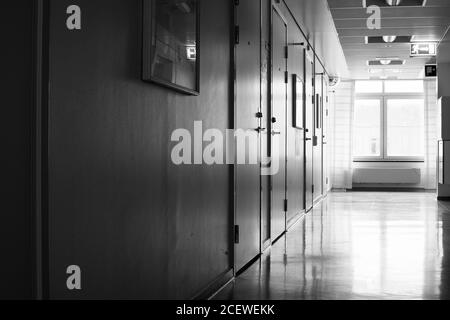 Couloir d'hôpital vide avec lumière vive d'une fenêtre en noir et blanc. Banque D'Images