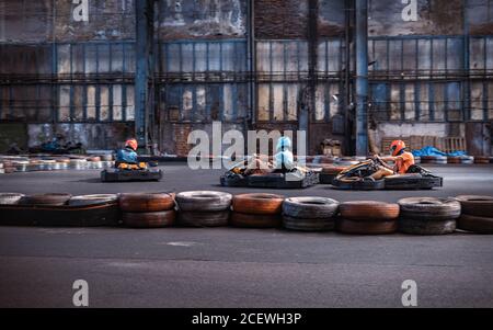 Trois gars se prennent les uns les autres sur une piste de karting intérieure Banque D'Images