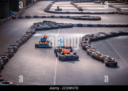 Trois gars se prennent les uns les autres sur une piste de karting intérieure Banque D'Images