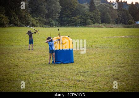 Petite fille tirant une flèche d'un arc pendant un jeu de tir à l'arc Banque D'Images