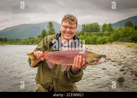 Un pêcheur heureux tenant un saumon rouge, capturé sur la rivière kitimat, en Colombie-Britannique, au Canada Banque D'Images