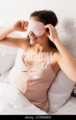 jeune femme enceinte en nightie touchant le masque rose pour les yeux Banque D'Images