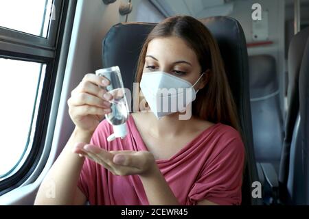 Voyager en toute sécurité dans les transports en commun. Jeune femme avec un masque KN95 FFP2 utilisant un distributeur de gel désinfectant pour les mains. Passager avec masque de protection disinf Banque D'Images