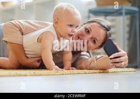 Portrait horizontal de niveau de la jeune mère heureuse prenant selfie avec son fils bébé, espace de copie Banque D'Images