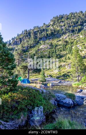 Camping avec tente à côté de la rivière glaciaire dans le paysage de montagne près du refuge Wallon Marcadau situé dans la belle vallée des Pyrénées françaises, sur le Haut Banque D'Images