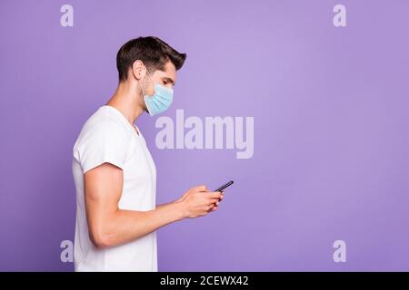 Profil vue latérale portrait d'un homme focalisé portant un masque de sécurité à l'aide de l'application 5g de l'appareil, commandez un séjour de livraison dans la boutique en ligne lumière vive et éclatante, isolée à la maison Banque D'Images