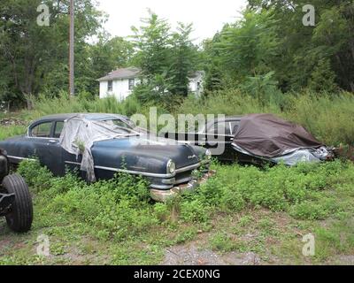 Abandon de voitures classiques dans un champ dans le comté de Sussex, dans le New Jersey. Une Trans Am Pontiac Firebird blanche et deux produits Chrysler anciens s'écaillent. Banque D'Images